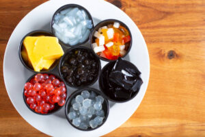 A top-down view of a plate holding a variety of popular bubble tea toppings and ingredients.