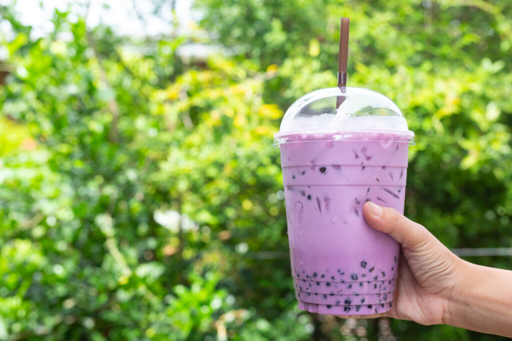 A hand holding blueberry flavor of bubble tea in the noon